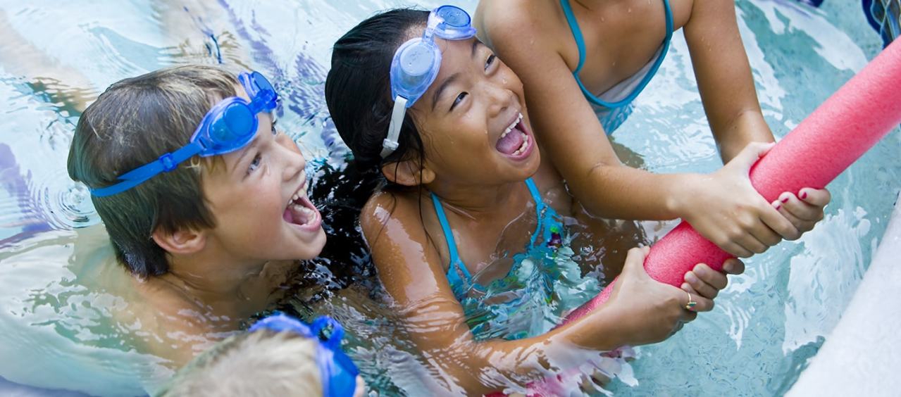 Lapset tarttumassa vaahtomuovileluun uima-altaassa