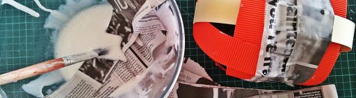 A papier mache mask being made with glue and newspaper.