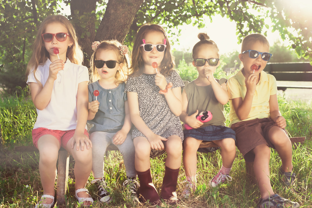 grupo de crianças lambendo pirulitos com óculos de sol