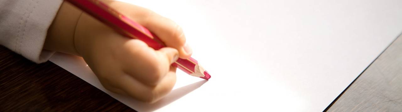 A child about to draw on white paper with a pink pencil.
