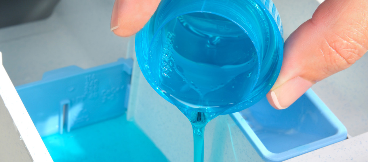 Person pouring laundry detergent into a washing machine drawer