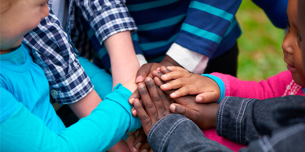 Children with their hands in a circle on top of each other