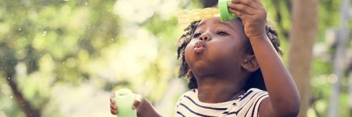 Young girl blowing bubbles and playing in the garden. 