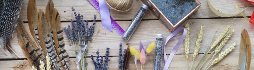 Colourful feathers, lavender, and glitter laid out on a wooden table.