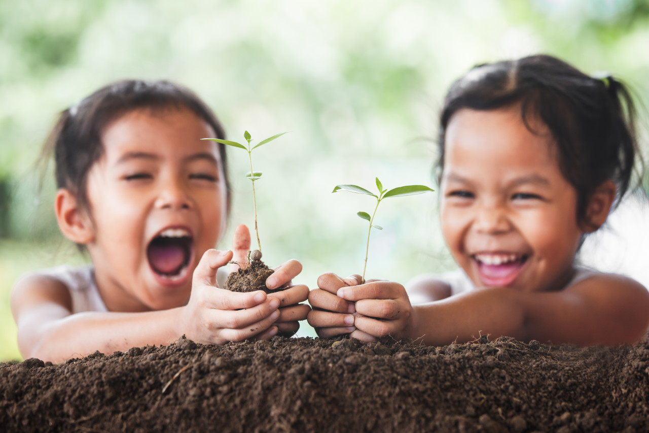 Kaksi lasta hymyilee kasvavalle kasville