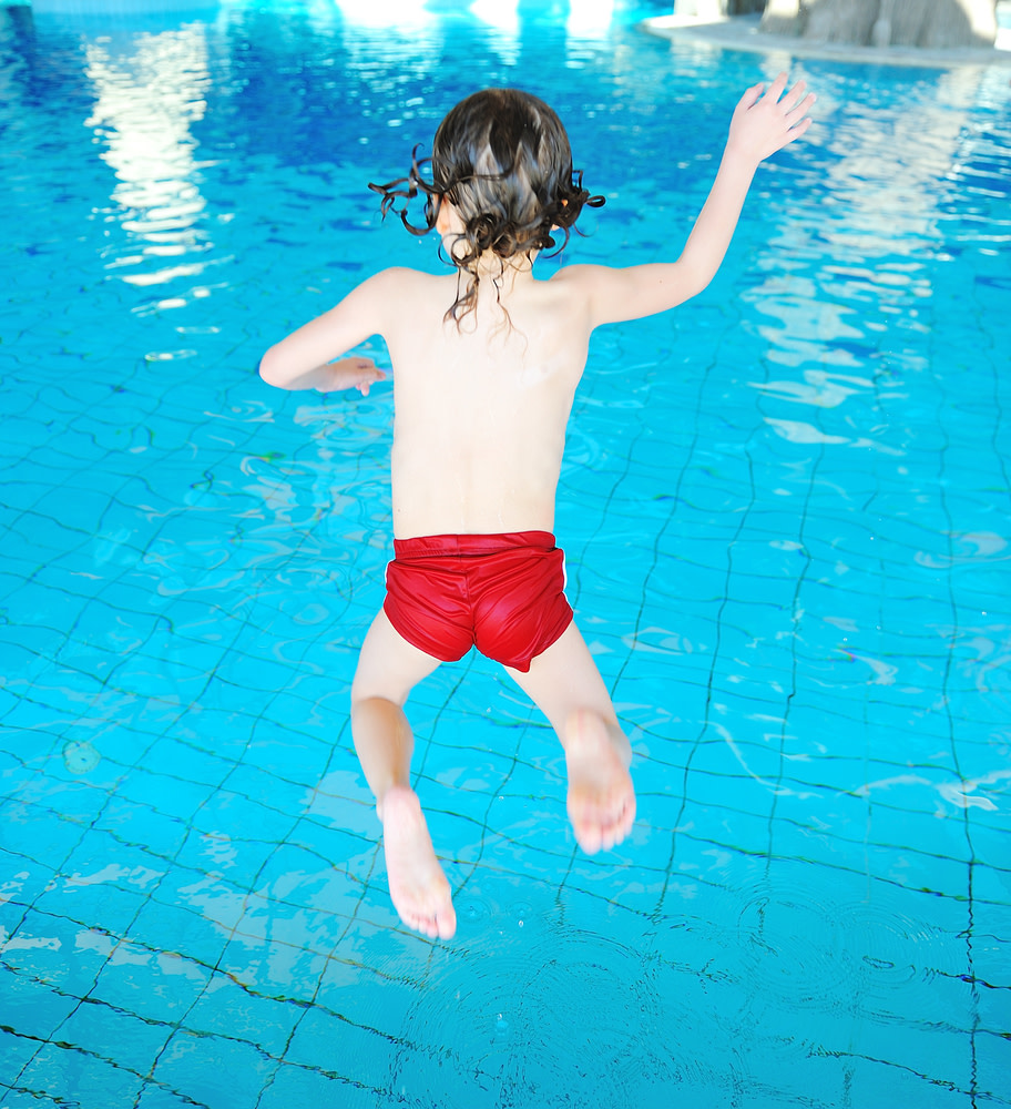Lapsi hyppää uima-altaalle