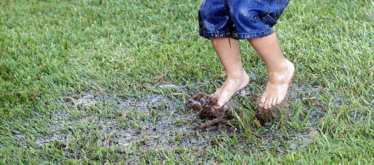Children jumping in a muddy puddle