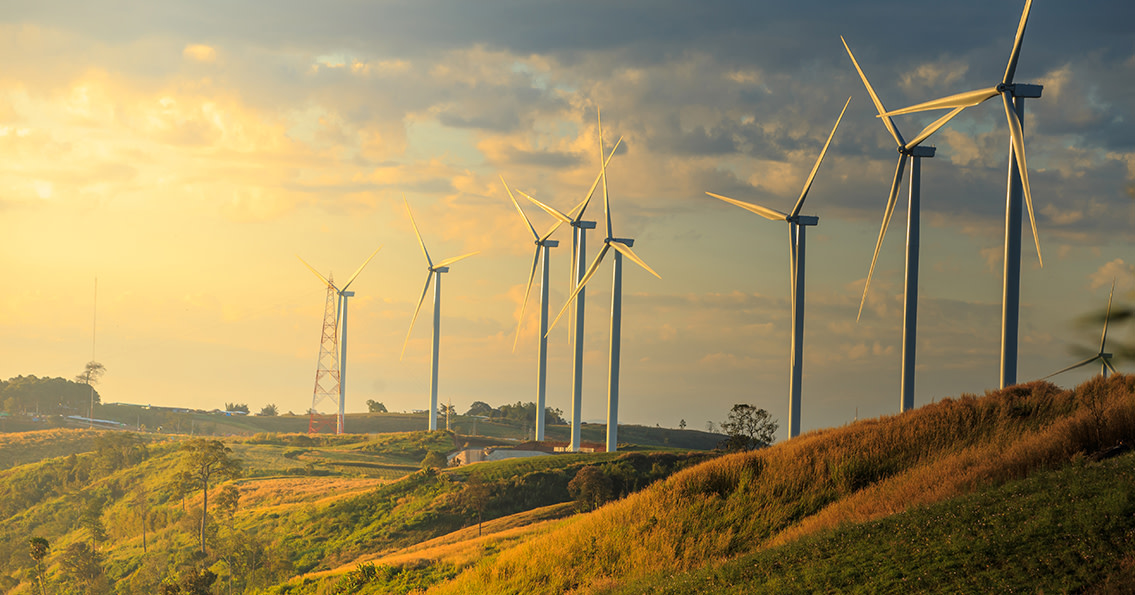 A wide-angle shot of wind turbines on some hills