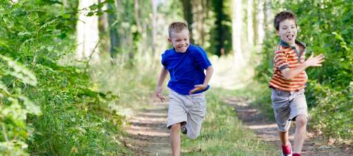 Excited boys running through a forest.