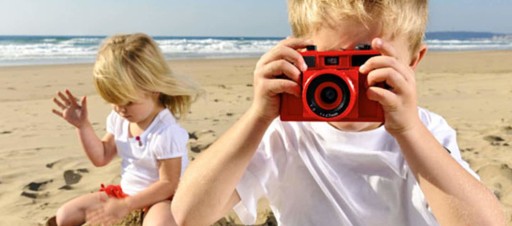 nenes jugando en la playa con cámara de fotos de juguete