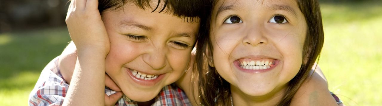 A young boy and a girl hugging in a park.