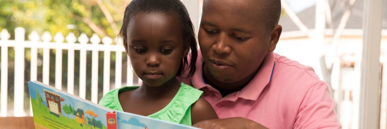 A general image of a man and a little girl reading a book.