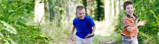 Two happy boys running in a forest.