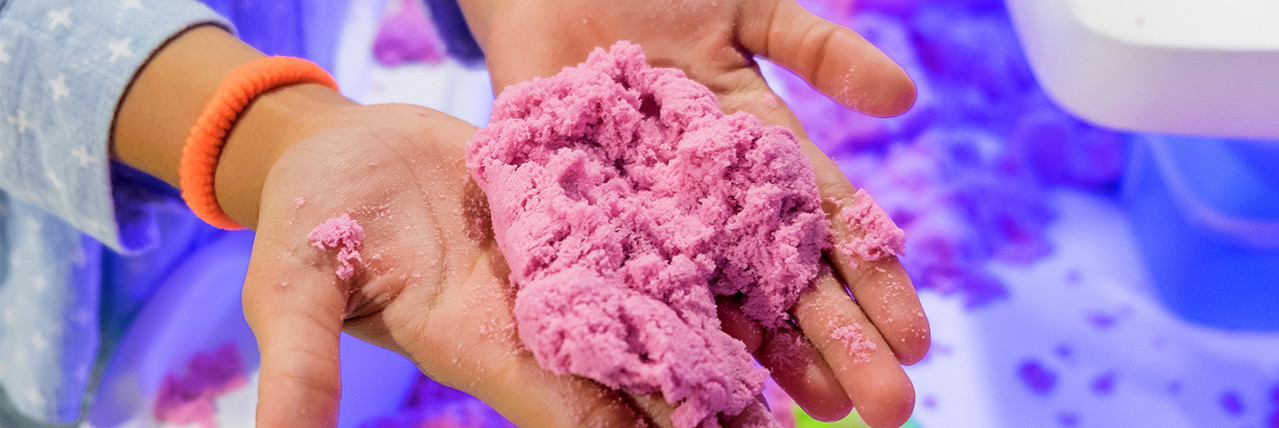 A person holding sand in their hands.