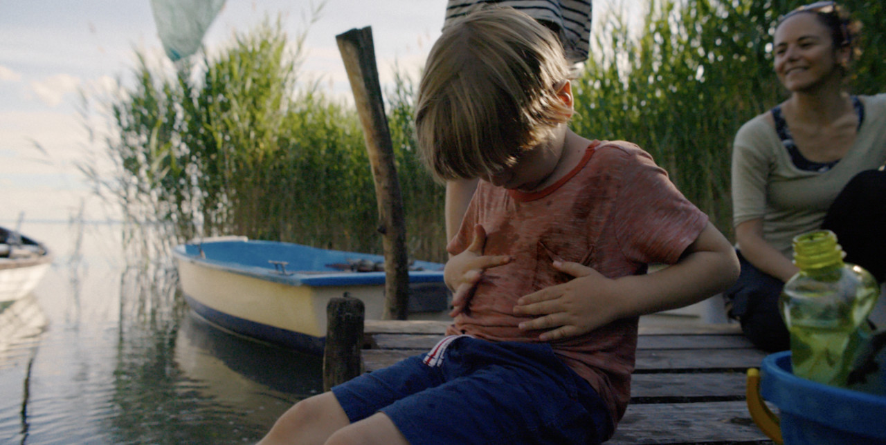 Pikkupoika istui järven rannalla likaantumassa t-paitaansa