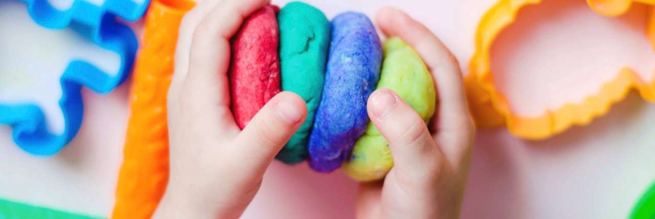 Childs hands playing with brightly coloured home-made dough