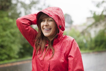Uma mulher sorridente com capa de chuva vermelha.