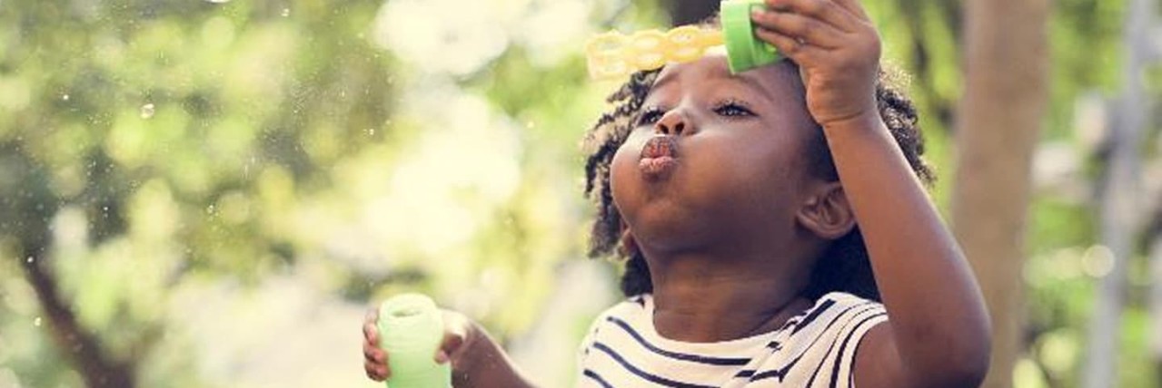 Young girl blowing bubbles and playing in the garden. 