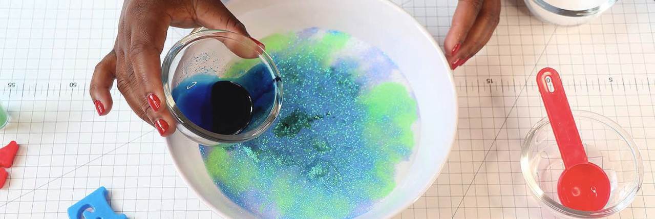 purple and green slime squeezed in kid's hands