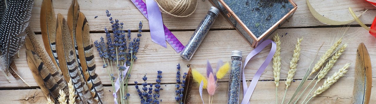 Colourful feathers, lavender, and glitter laid out on a wooden table.