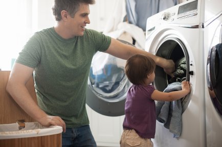 Pai e filho colocando roupa na máquina de lavar