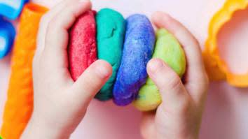 Childs hands playing with brightly coloured home-made dough