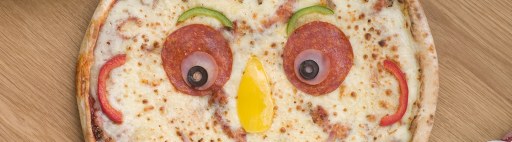 A pizza with toppings arranged in the shape of a face.